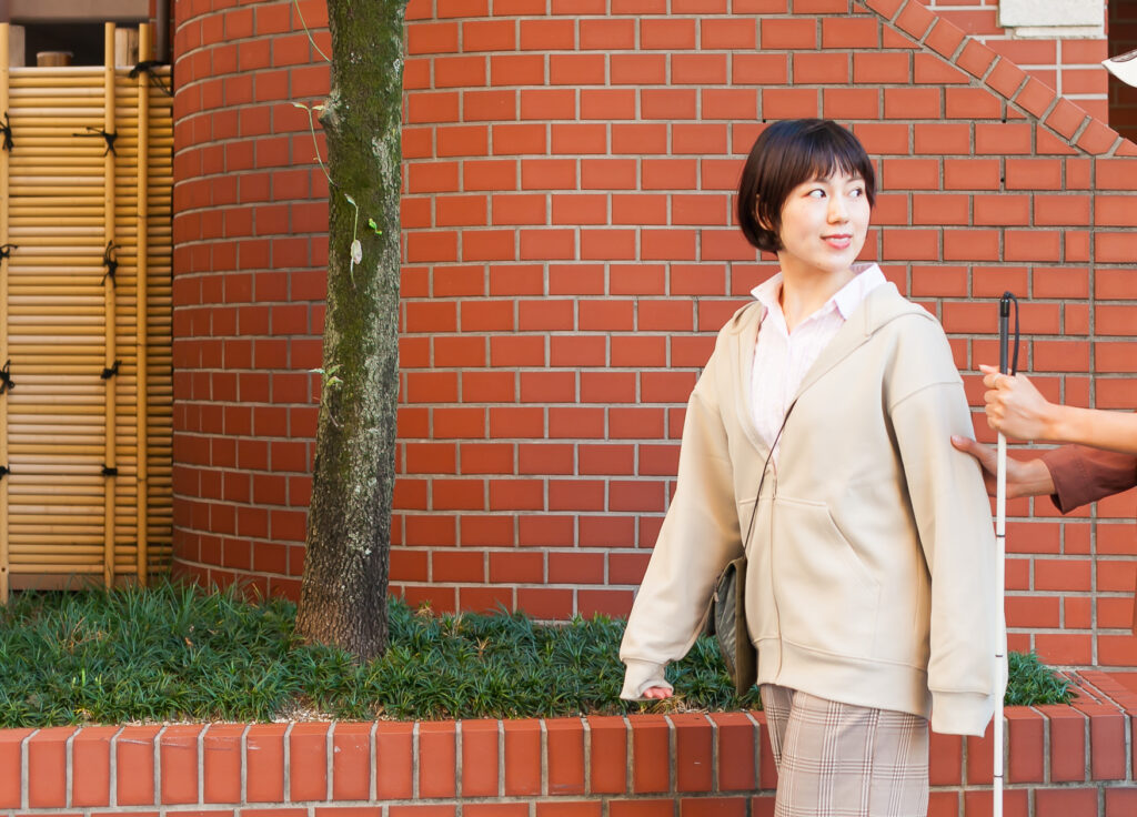 街なかで視覚障害者を誘導するガイドヘルパーの横顔の画像。