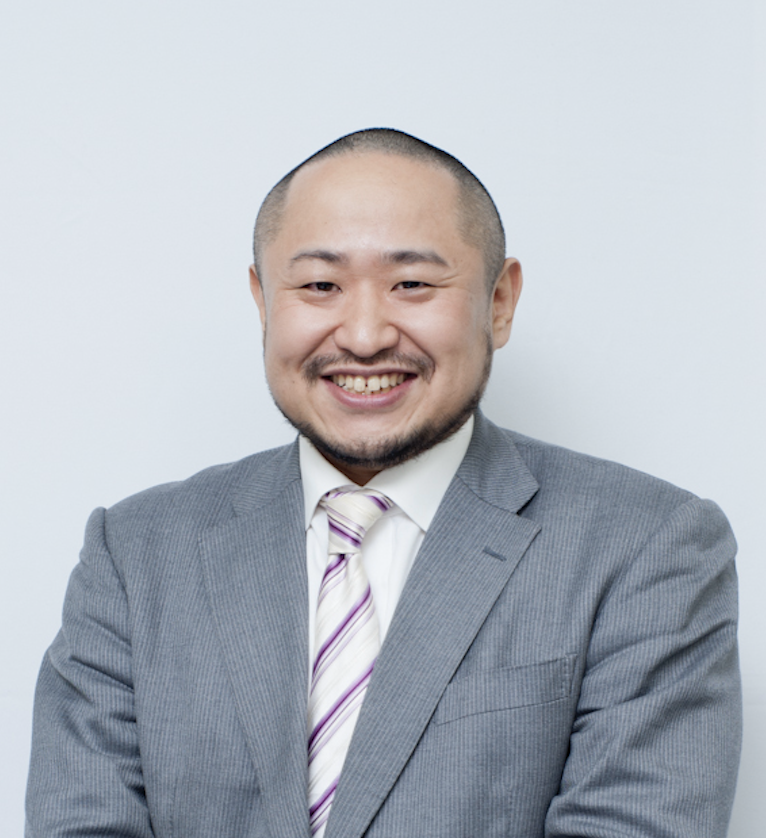 理事の初瀬がスーツ姿で笑顔で写っている証明写真のような画像。